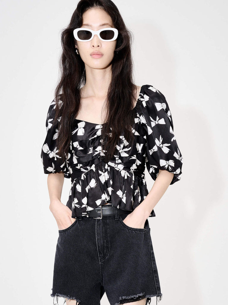 MO&Co. Women's Bowknot Print Cropped Top with Puff Sleeve in Black will enhance your style with a chic bowknot print and feminine heart-shaped neckline. The silk blend material ensures a comfortable fit, while the pleated details and back self-tie knot add a unique touch of elegance.