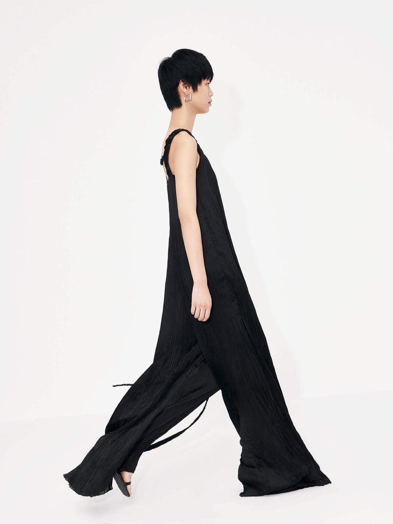 MO&Co. Women's Textured Wide Leg Jumpsuit in Black features an included belt & double side pocket design. Its elegantly draped & twisted shoulder strap completes the look for a timeless classic.