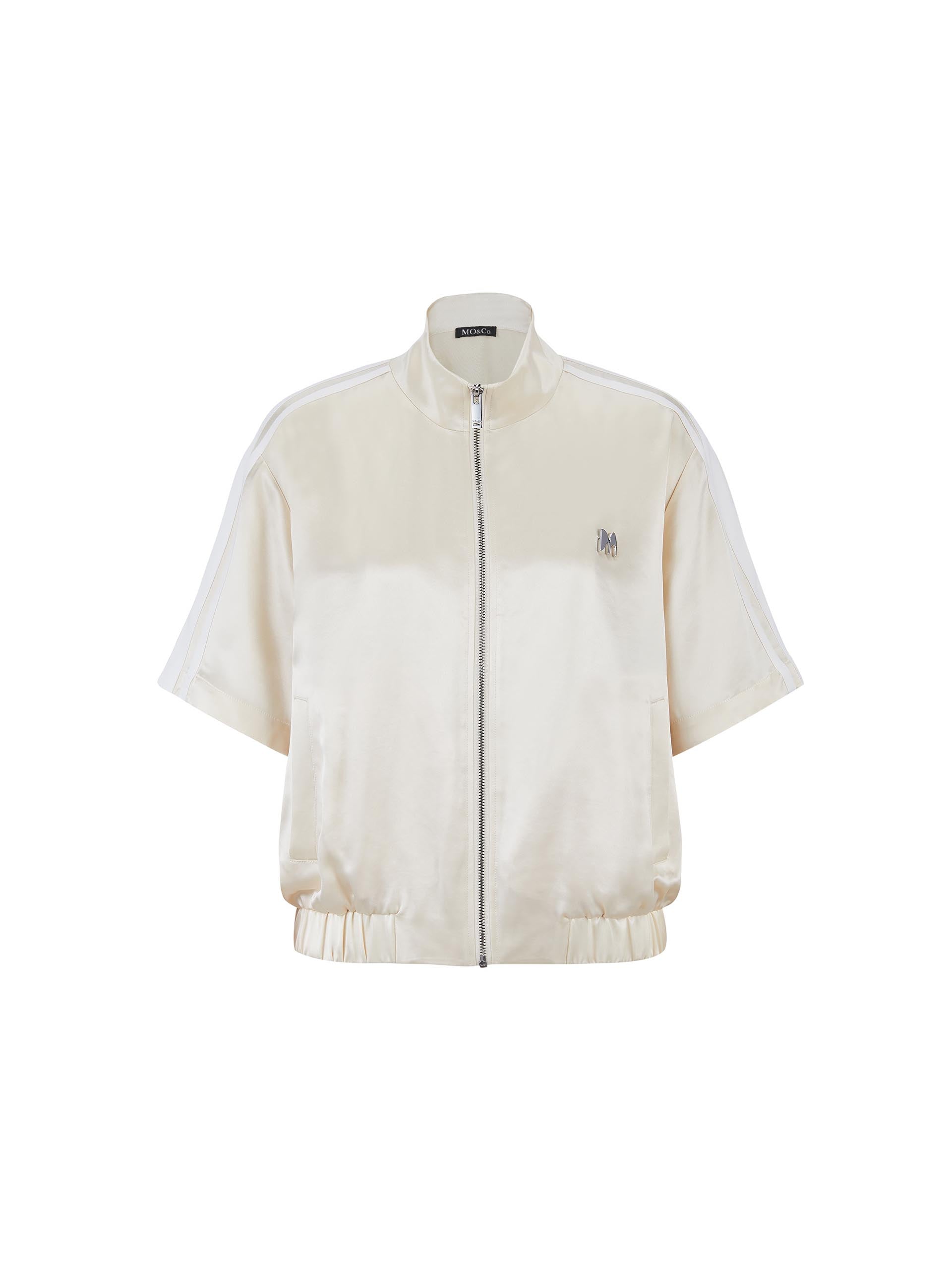 MO&Co. Women's Satin Acetate Blend Casual Track Jacket in Short Sleeves in Beige. Features: Loose fit, contrasting trim design, elasticized hem, side pockets & zip closure, and an acetate blend fabric for softness & comfort.