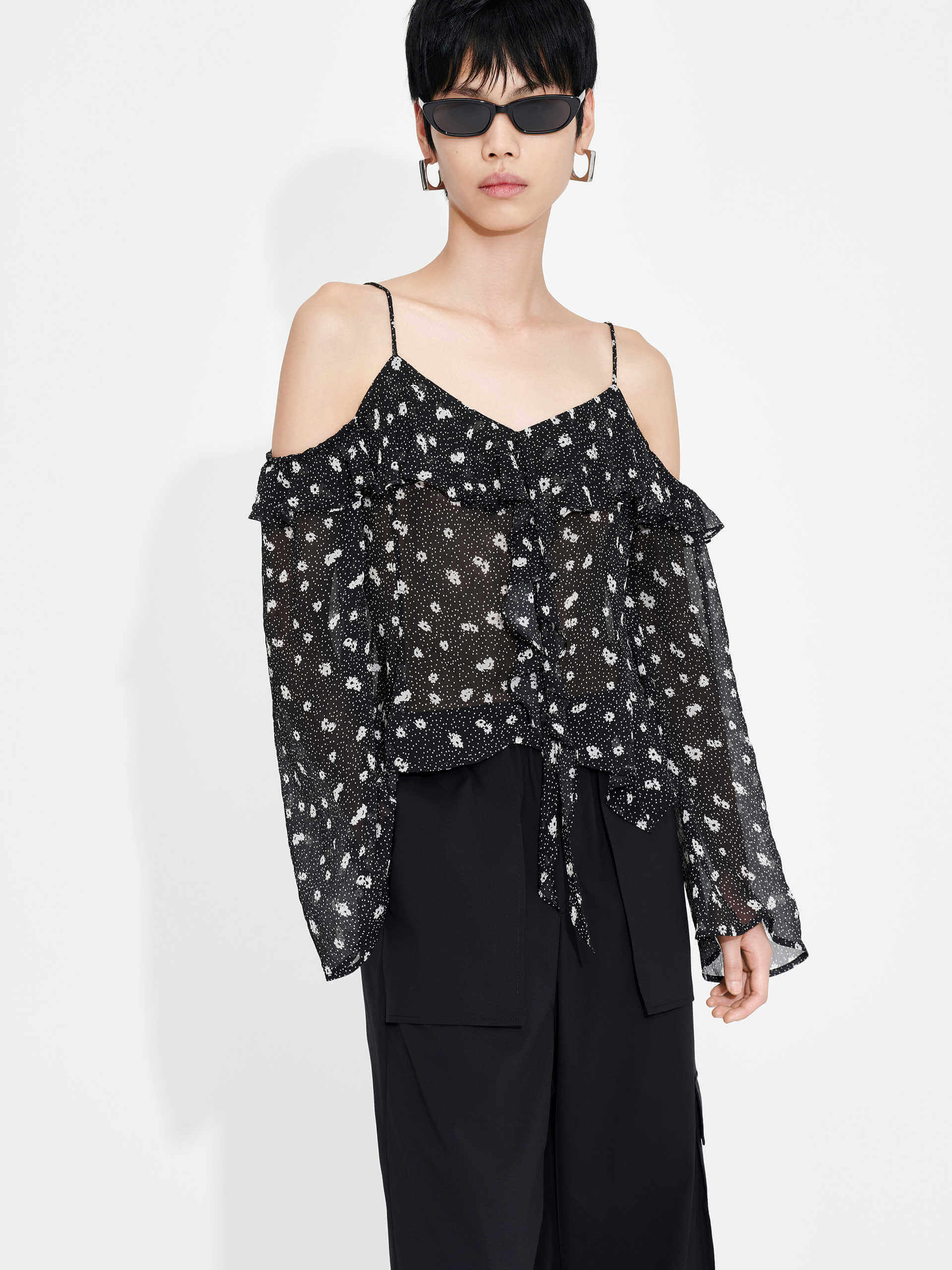 This MO&Co. Cut Shoulder Printed Top in Black is crafted from 100% recyclable fibers, making it a stylish and sustainable choice. Show off your fashion-forward style with off-shoulder trumpet sleeves, a floral and polka dot print, and pleated trim detailing on the front. Elevate your wardrobe with this statement piece!