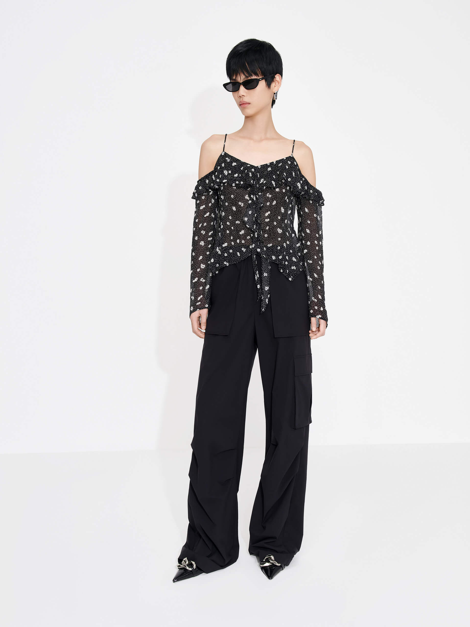 This MO&Co. Cut Shoulder Printed Top in Black is crafted from 100% recyclable fibers, making it a stylish and sustainable choice. Show off your fashion-forward style with off-shoulder trumpet sleeves, a floral and polka dot print, and pleated trim detailing on the front. Elevate your wardrobe with this statement piece!