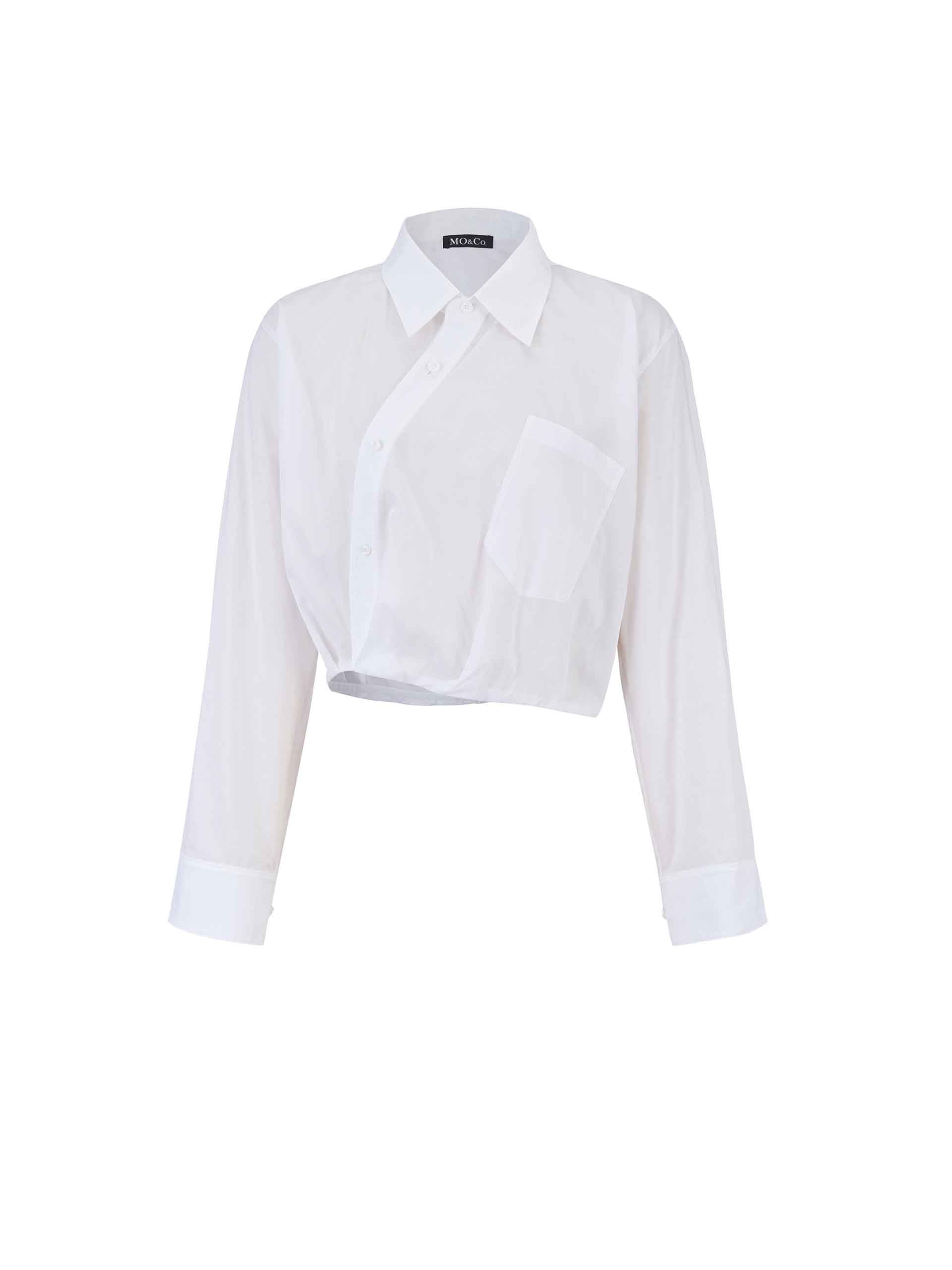 MO&Co. Women's Slanted Placket Cropped Shirt in White. Crafted with a stylish cropped silhouette and slanted placket design, this fashion-forward piece is bound to turn heads. Plus, it's complete with a front pocket and elastic hem for a unique look.