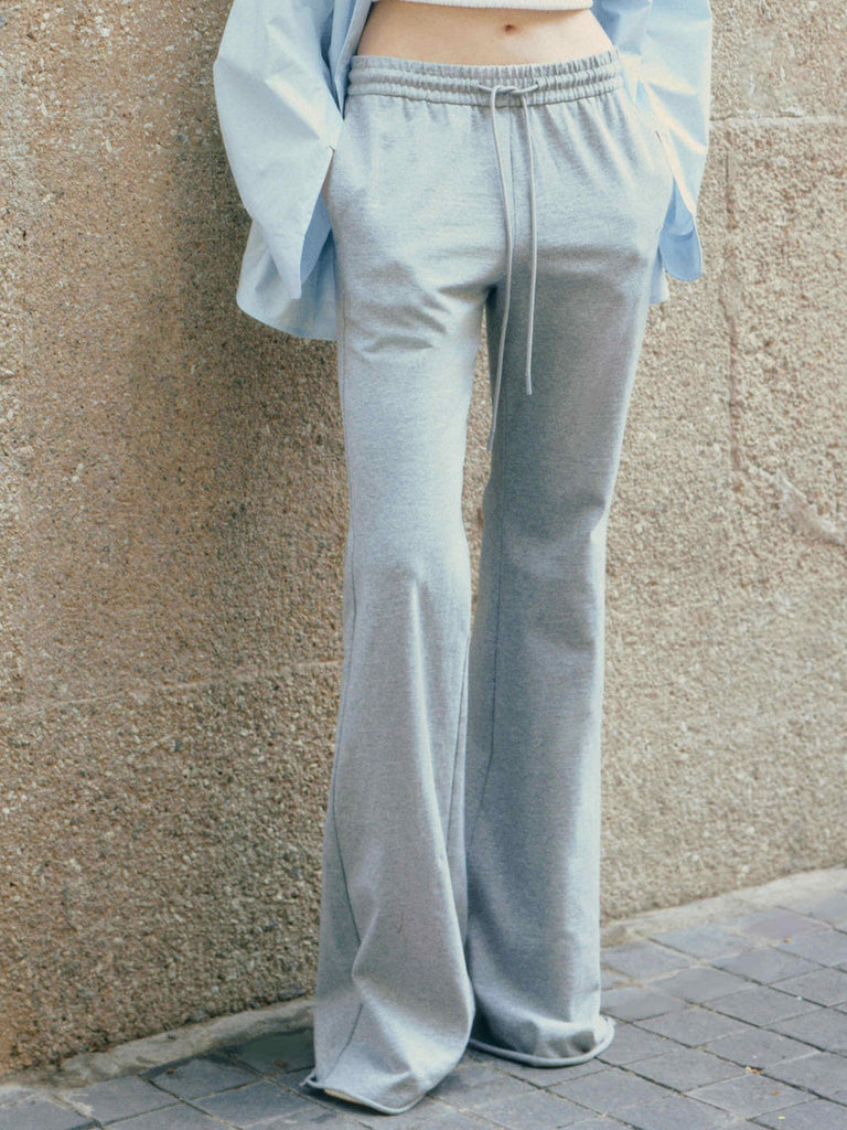MO&Co.'s Drawstring Waist Causal Flared Sweatpants in Grey. Crafted from soft cotton, these trousers feature a relaxed fit with drawstrings and elastic waistband for comfort. They also come with flared legs and double side pockets with MC embroidery details.