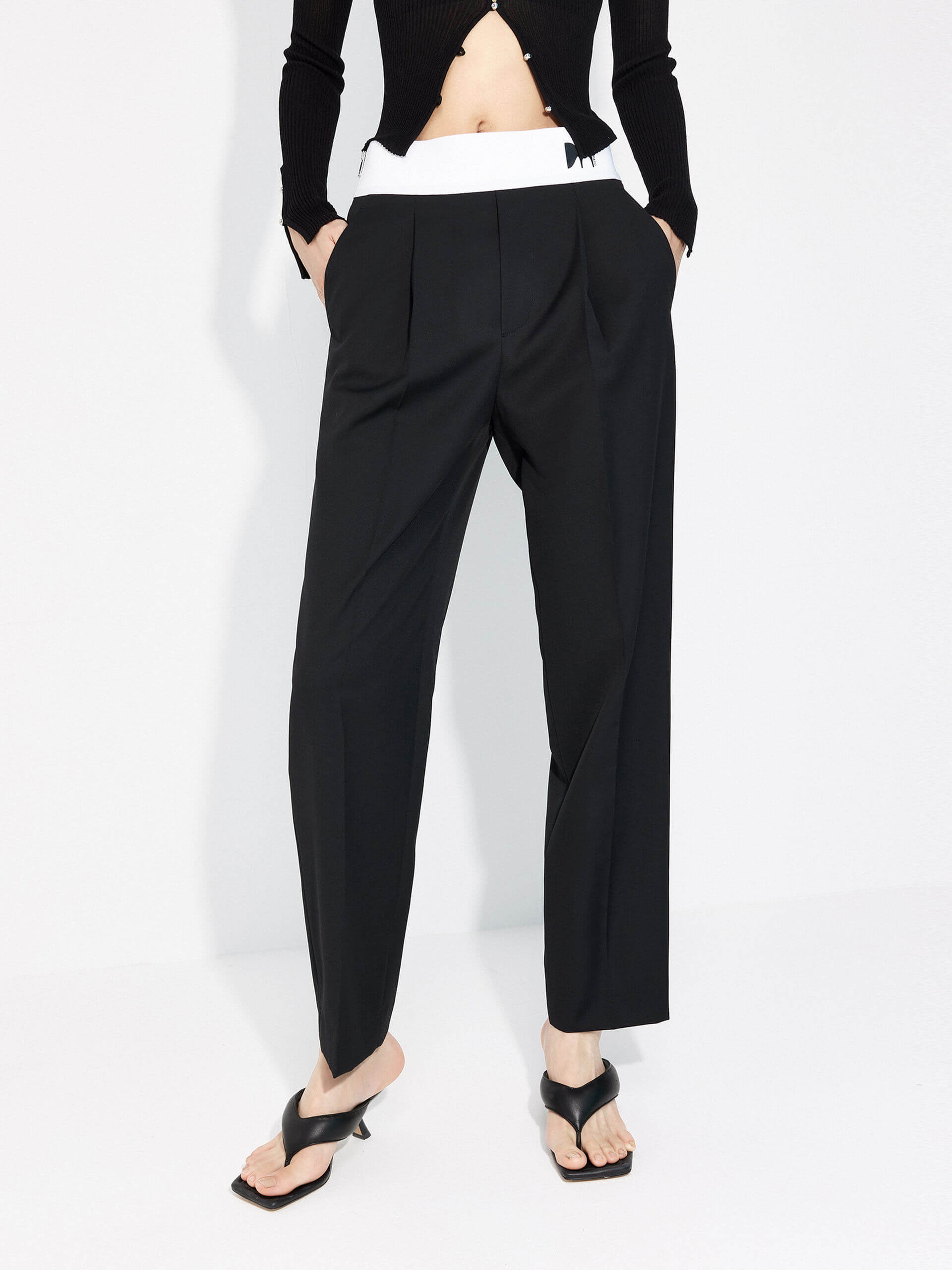 MO&Co. Women's Contrasting Details Suit Pants in Black. Crafted with a luxurious wool blend and featuring an eye-catching elastic waistband with an M pattern, these pants are designed for comfort and style. Double-side pockets and side zip closure complete the look.