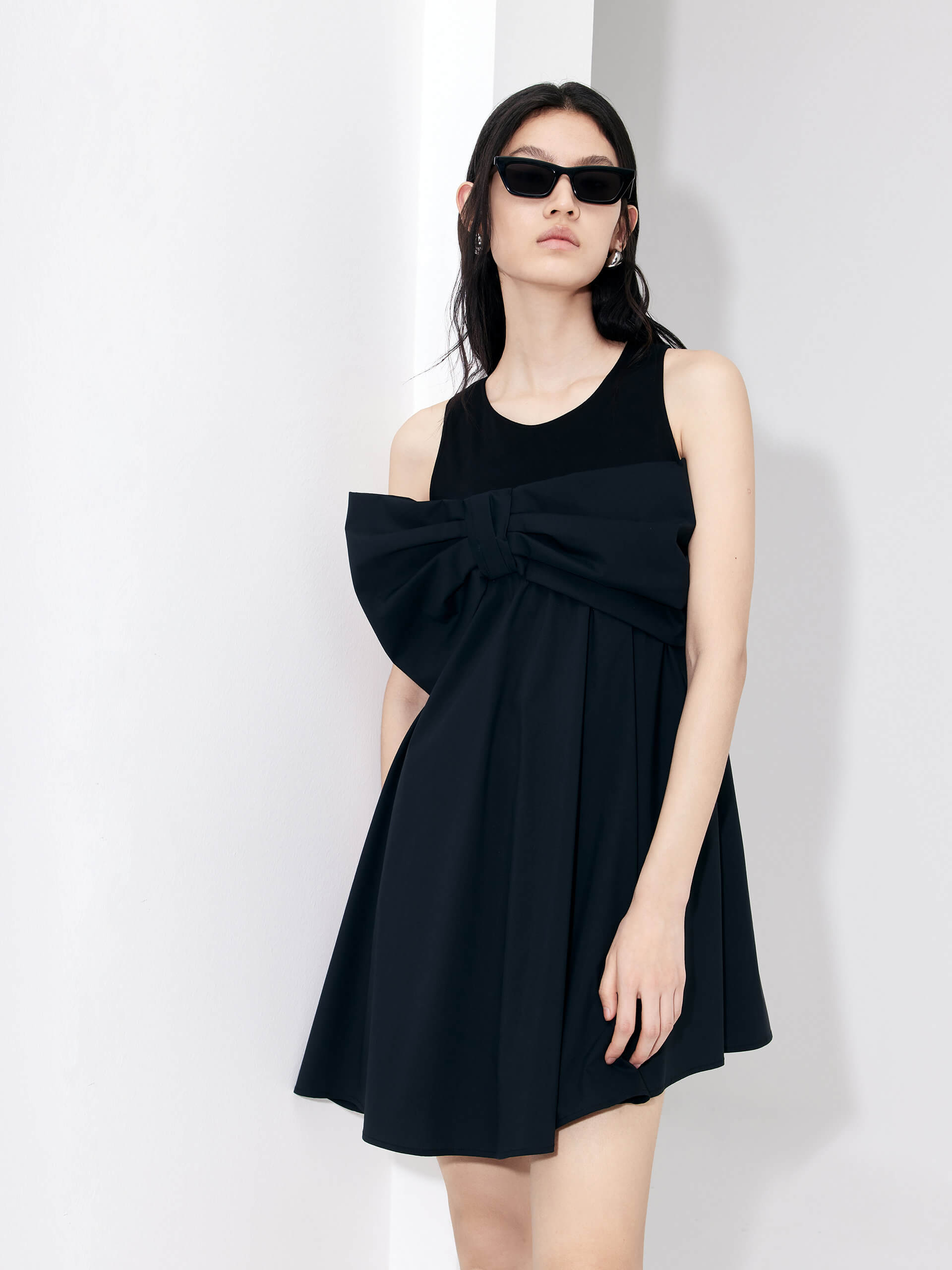 MO&Co. Bowknot Front Mini Dress in Black with sleeveless design. Crafted from a soft and breathable cotton blend, this feminine and sophisticated piece features an a-line silhouette with bowknot front details for an eye-catching look.