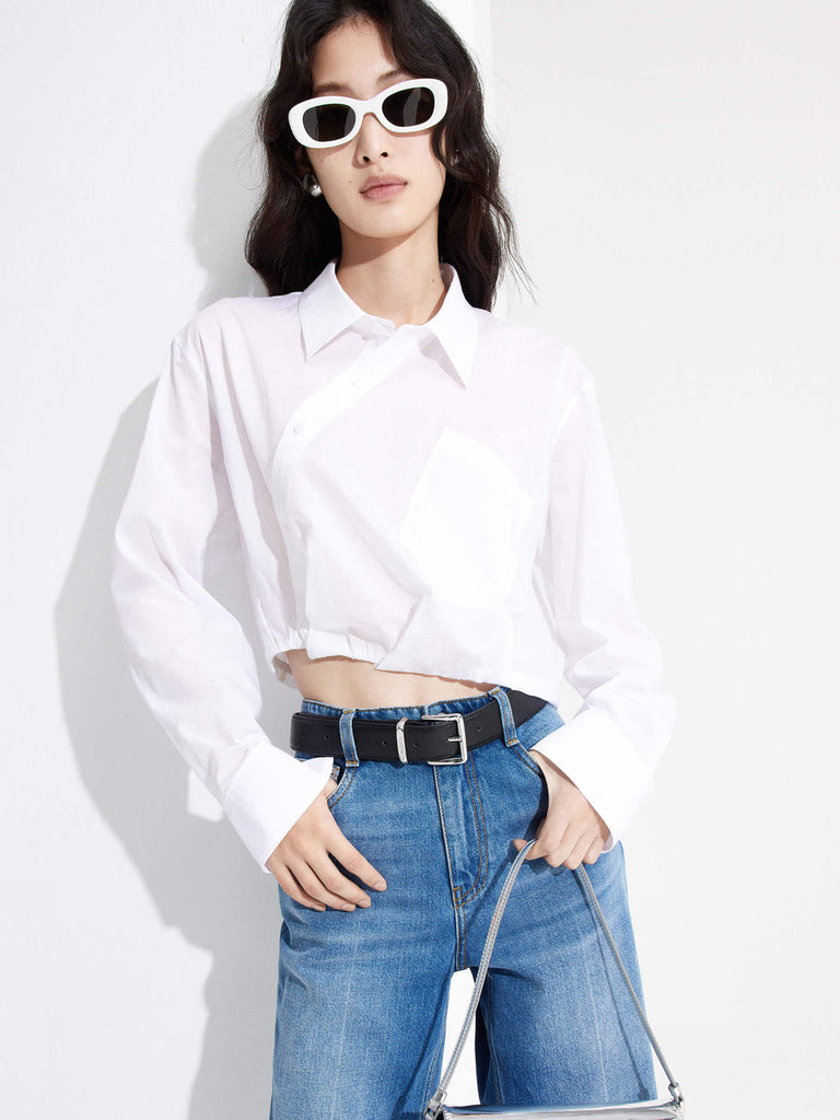 MO&Co. Women's Slanted Placket Cropped Shirt in White. Crafted with a stylish cropped silhouette and slanted placket design, this fashion-forward piece is bound to turn heads. Plus, it's complete with a front pocket and elastic hem for a unique look.