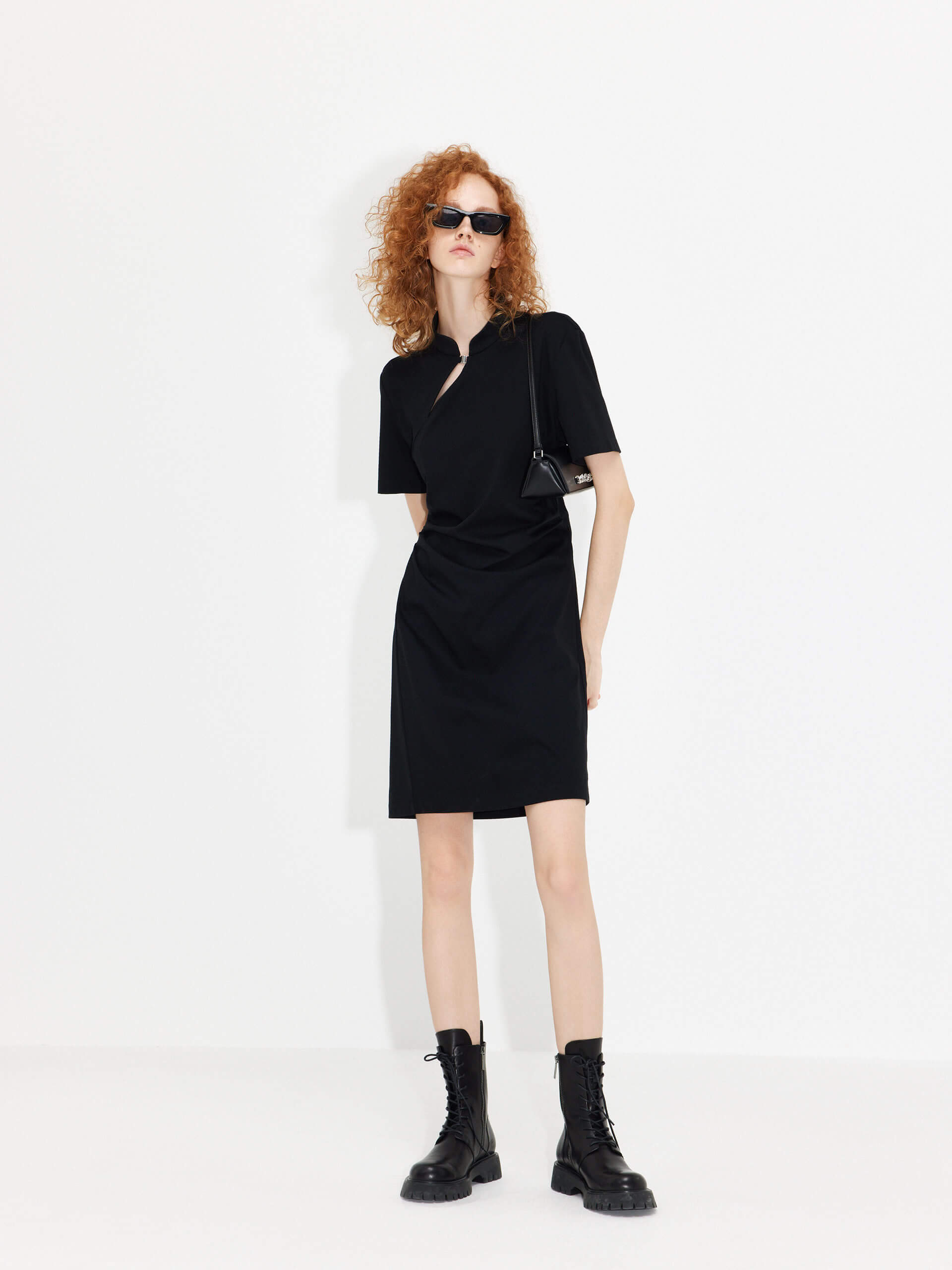 MO&Co. Women's Stand Collar Pleated Mini Dress in Black showcases an accentuated waistline, classic mandarin collar, and a unique slanted placket with metal button details for a perfect blend of classic and modern.