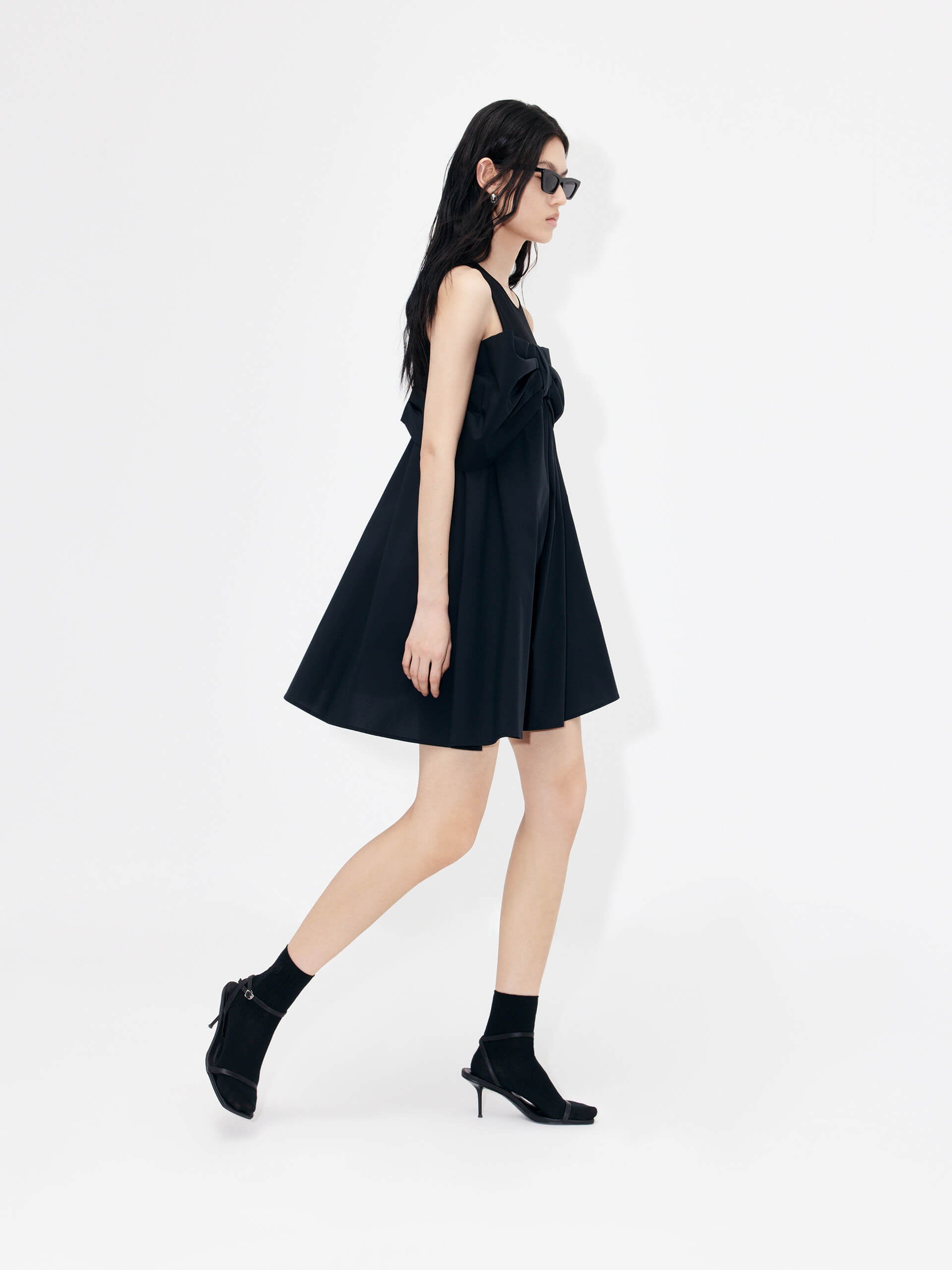 MO&Co. Bowknot Front Mini Dress in Black with sleeveless design. Crafted from a soft and breathable cotton blend, this feminine and sophisticated piece features an a-line silhouette with bowknot front details for an eye-catching look.