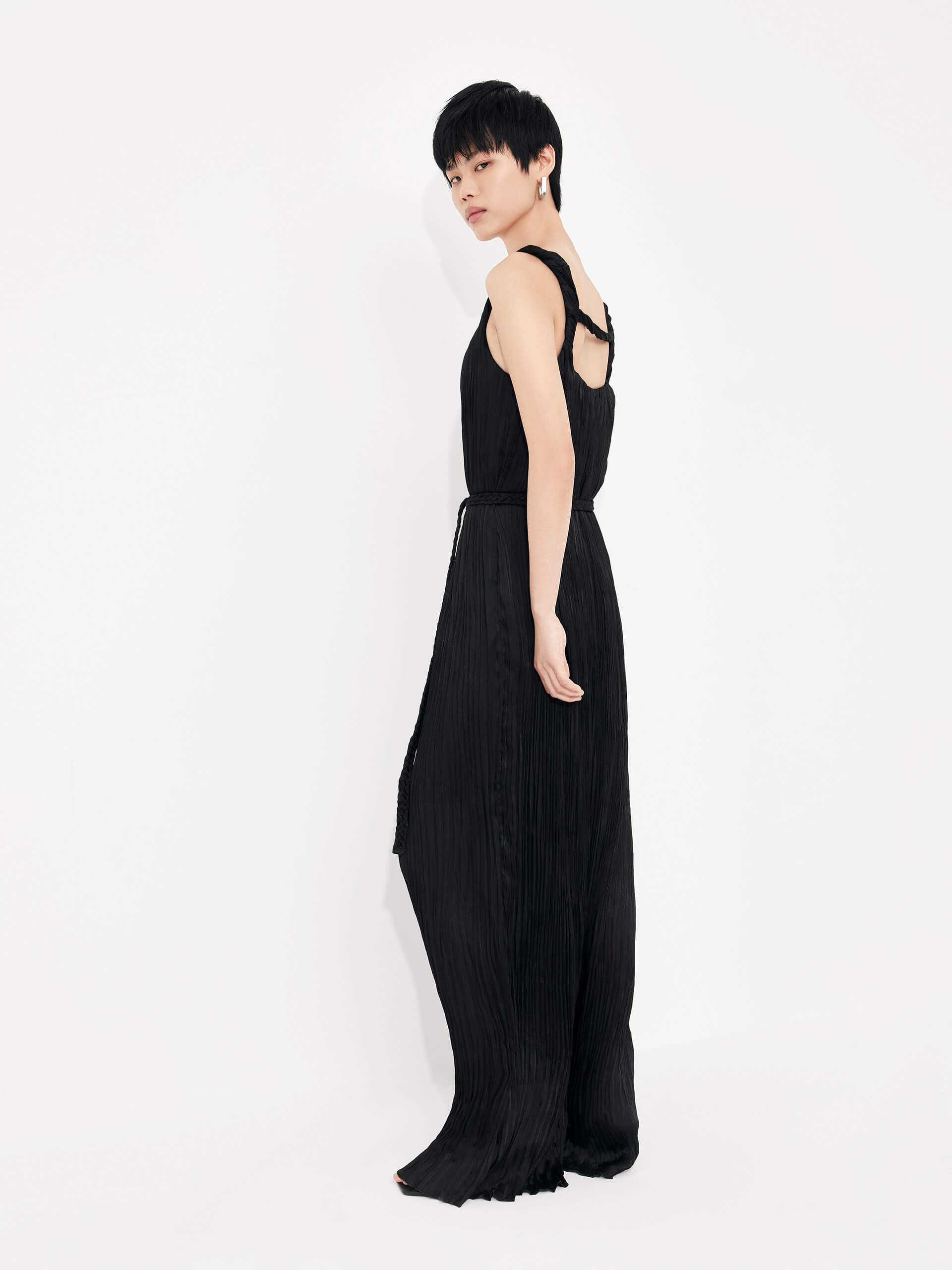 MO&Co. Women's Textured Wide Leg Jumpsuit in Black features an included belt & double side pocket design. Its elegantly draped & twisted shoulder strap completes the look for a timeless classic.