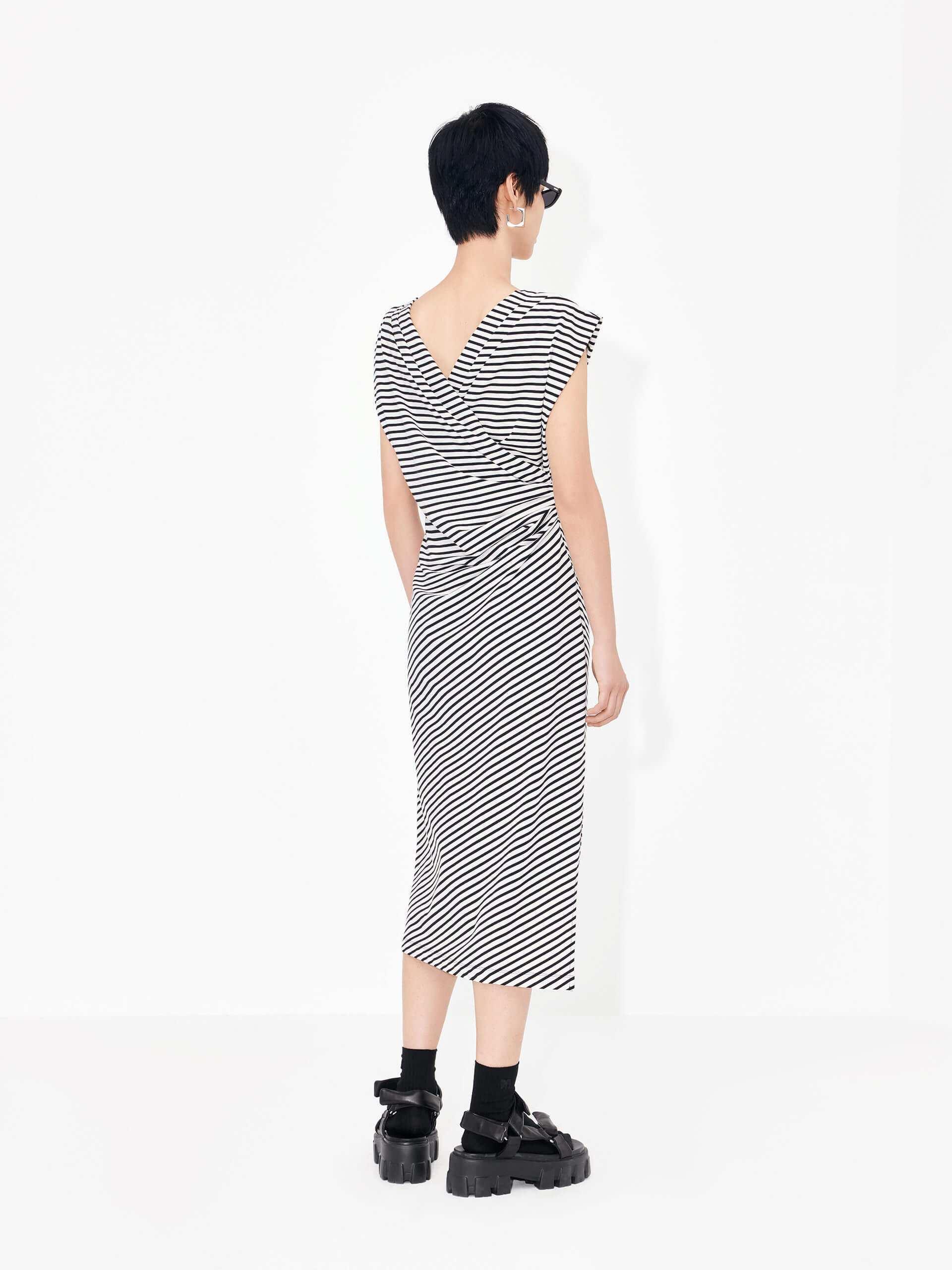 Be effortlessly elegant in this MO&Co. Gathered Waist Stripe dress in Classic Black and White. It features a timeless black and white striped pattern, a pleated gathering at the waist, a cross design at the back, and wide shoulders for a flattering silhouette.