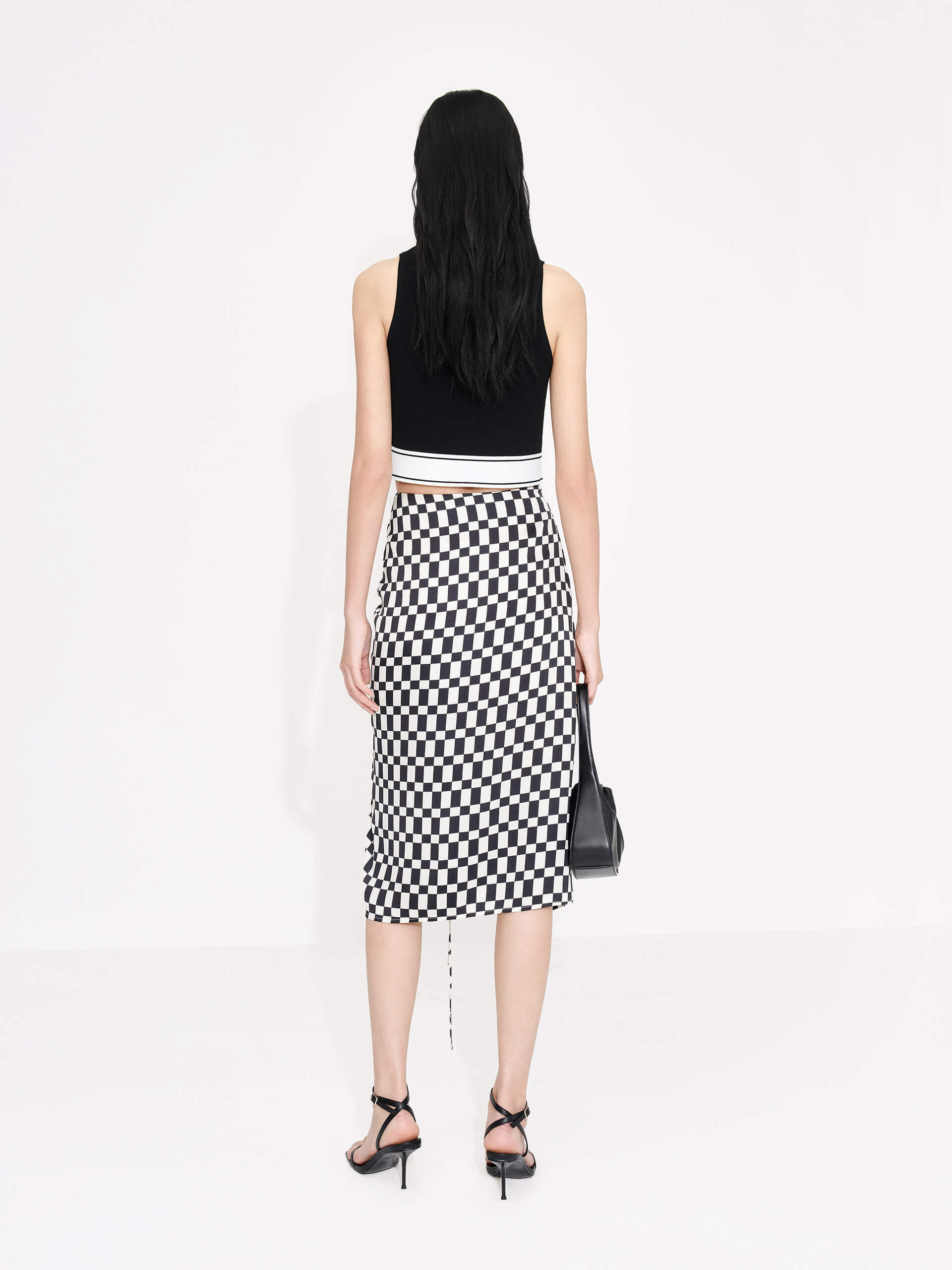 MO&Co. Women's Chessboard Pattern Skirt features modern bold chessboard pattern in black and white. Crafted with pleated drawstring design for an elegant look, finished with a hidden side zipper closure and side slit.