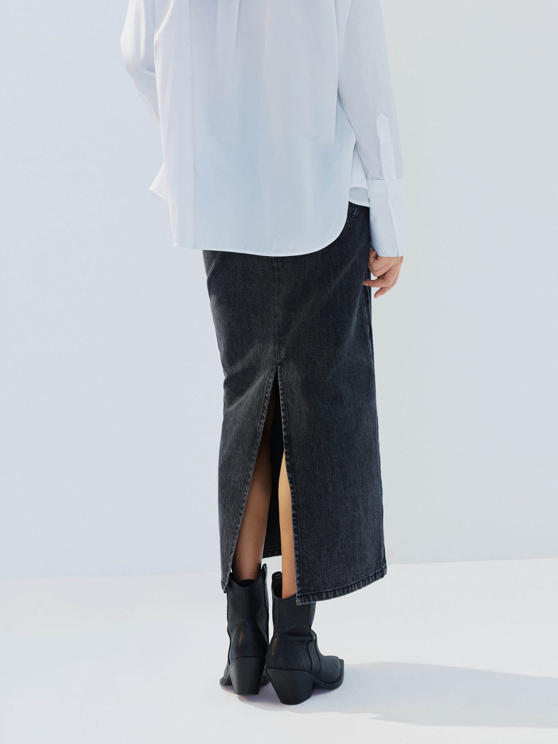 MO&Co. Noir Women's Straight Cut Denim Maxi Skirt Black Washed. Crafted from pure cotton, this skirt offers both comfort and style with its mid-length silhouette and side-washed fade effect.