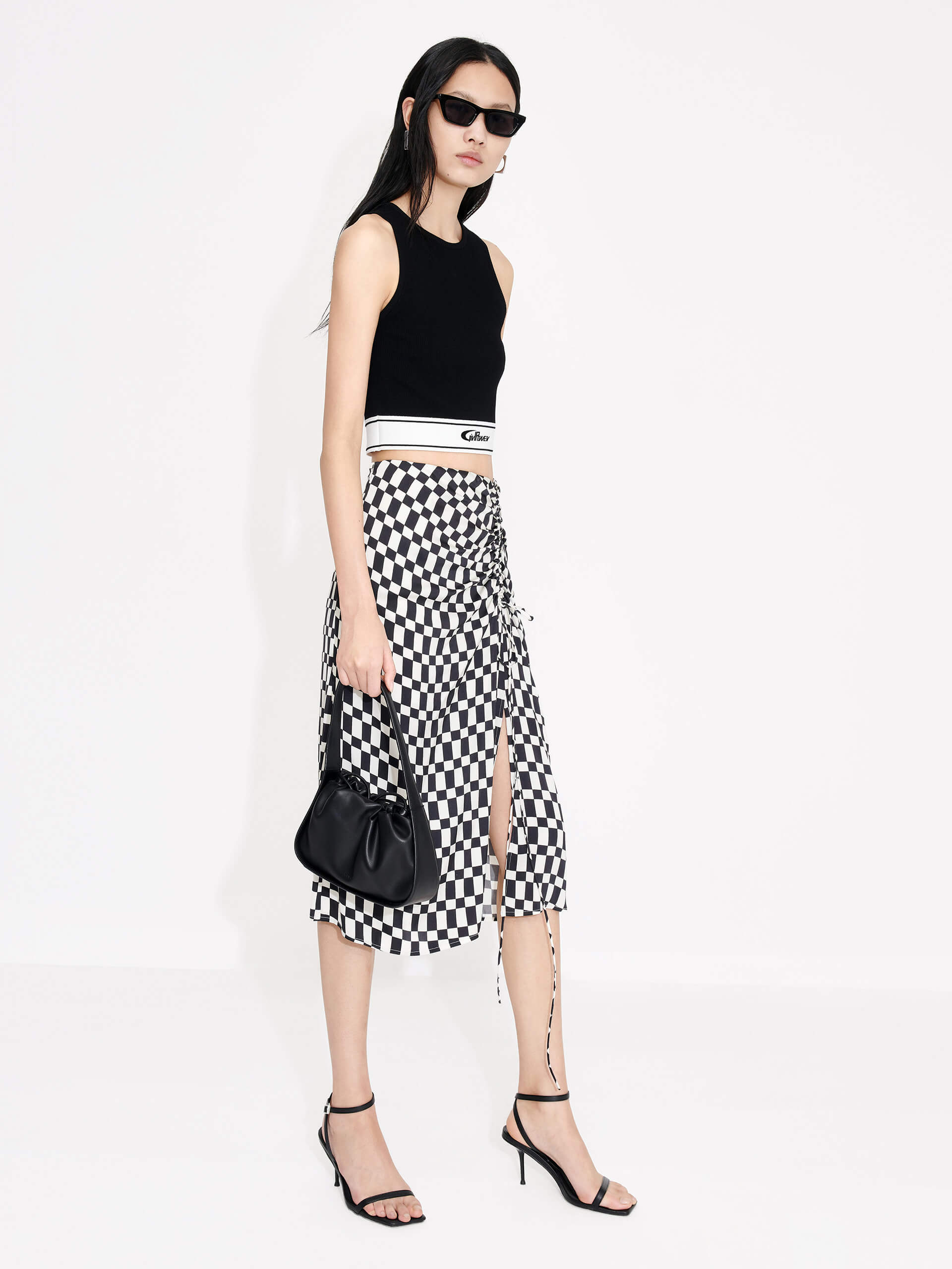 MO&Co. Women's Chessboard Pattern Skirt features modern bold chessboard pattern in black and white. Crafted with pleated drawstring design for an elegant look, finished with a hidden side zipper closure and side slit.