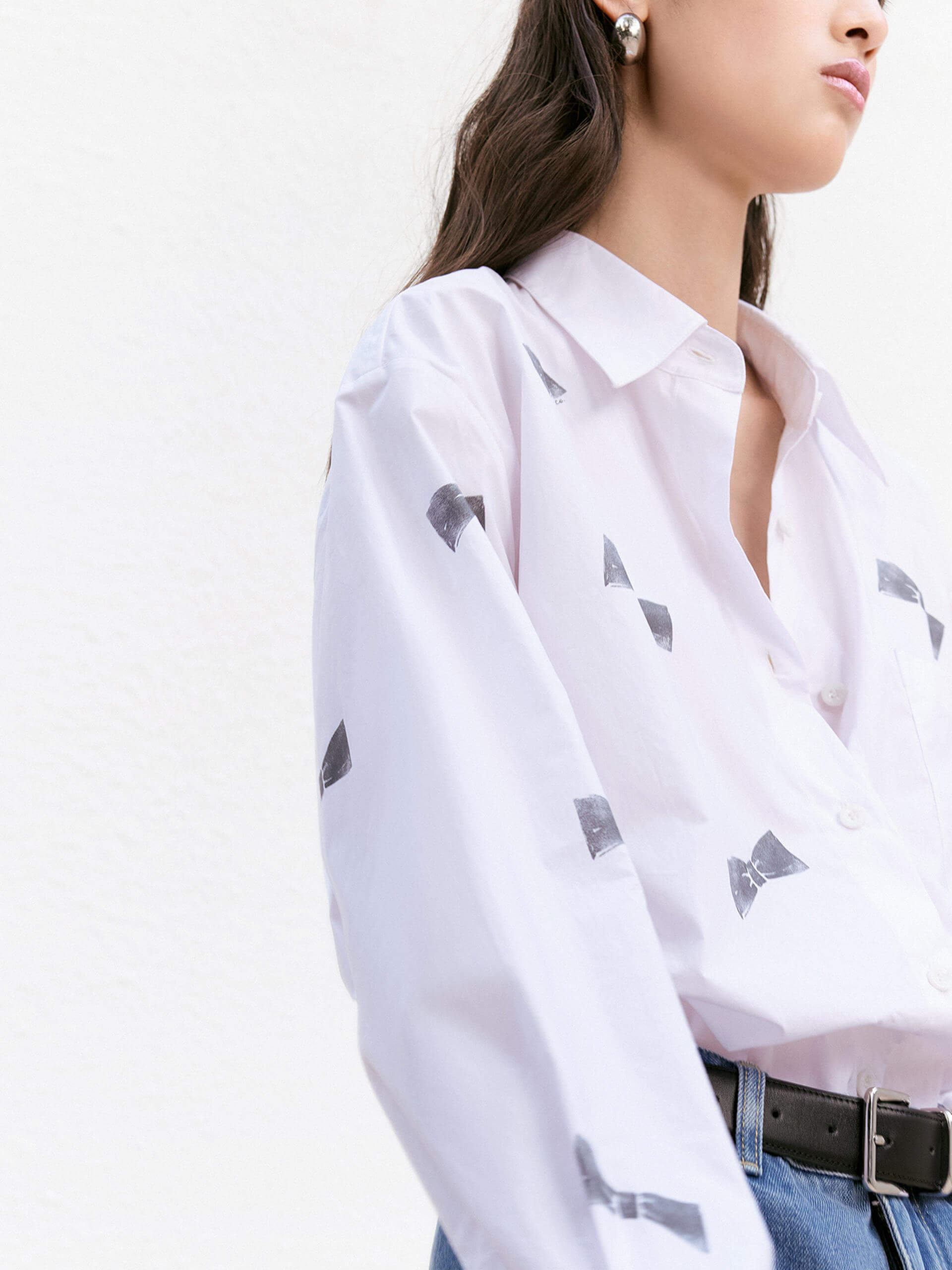 MO&Co. Women's Bowknot Pattern Cotton Shirt in White, with its all-over bowknot print design, comfortable cotton material and loose fit.