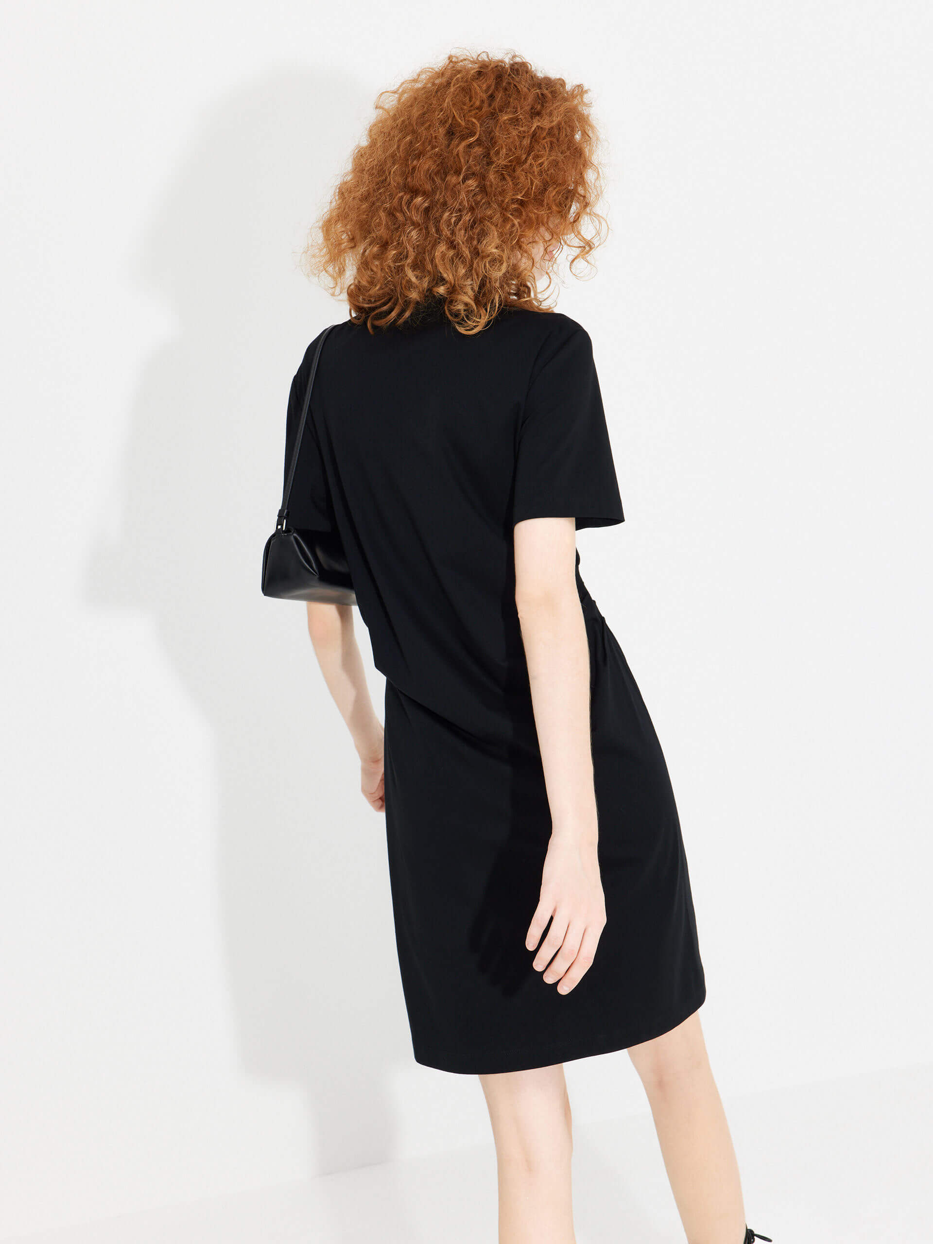 MO&Co. Women's Stand Collar Pleated Mini Dress in Black showcases an accentuated waistline, classic mandarin collar, and a unique slanted placket with metal button details for a perfect blend of classic and modern.