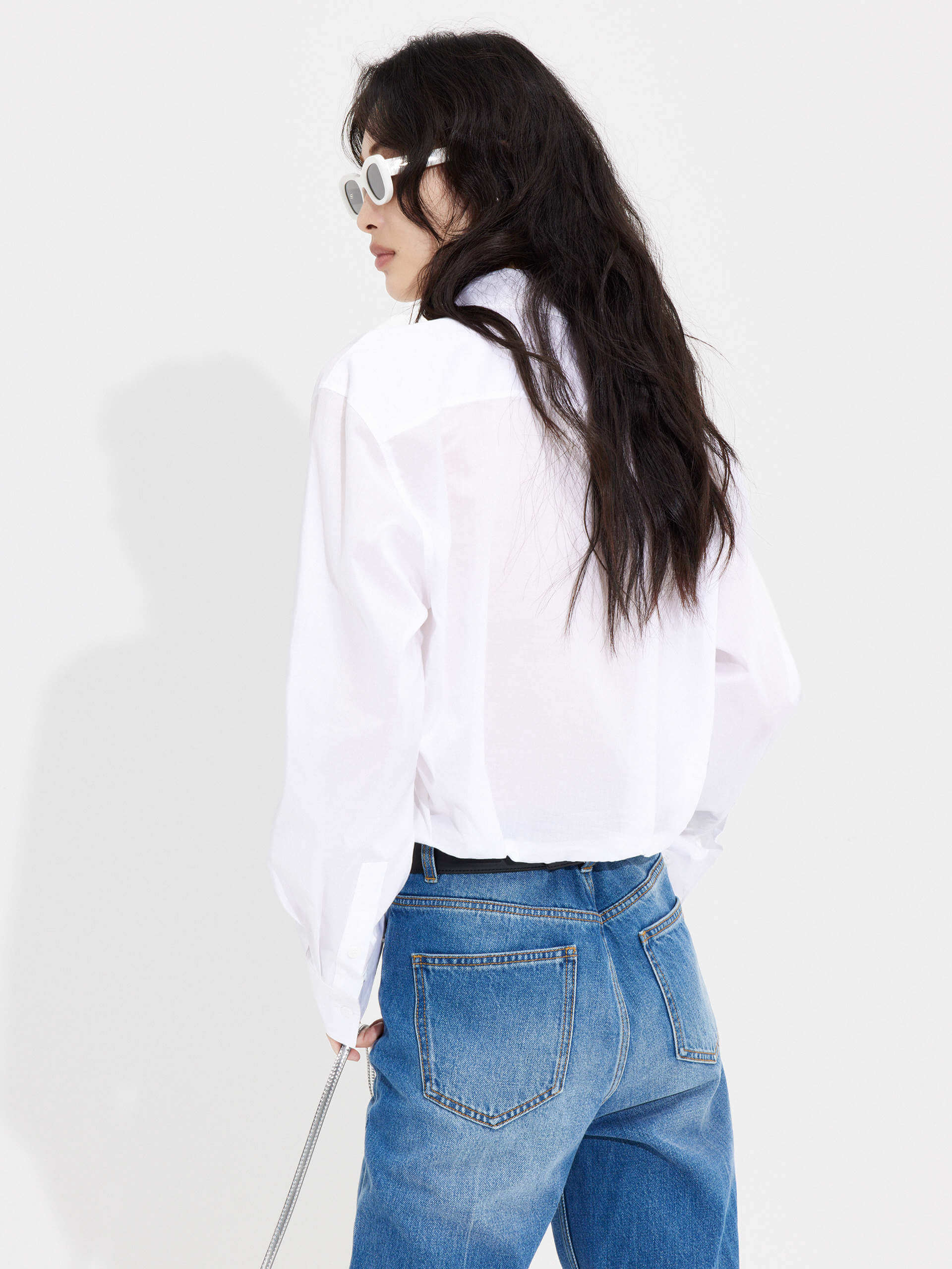 MO&Co. Women's Slanted Placket Cropped Shirt in White. Crafted with a stylish cropped silhouette and slanted placket design, this fashion-forward piece is bound to turn heads. Plus, it's complete with a front pocket and elastic hem for a unique look.