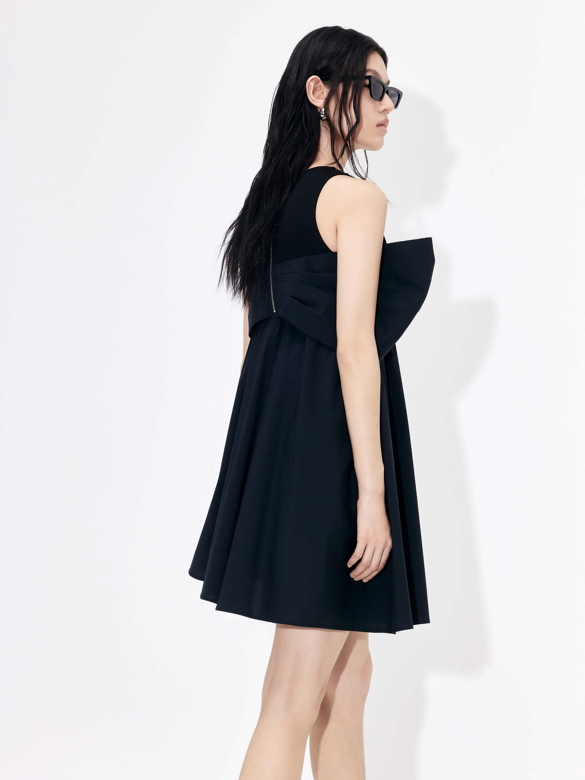 MO&Co. Bowknot Front Mini Dress in Black with sleeveless design. Crafted from a soft and breathable cotton blend, this feminine and sophisticated piece features an a-line silhouette with bowknot front details for an eye-catching look.