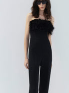 MO&Co. Noir Women's Feather Detail Fitted Jumpsuit Black features feather embellishments and a sleek straight-leg, strapless silhouette with a flattering fitted waist, ideal for a night out.