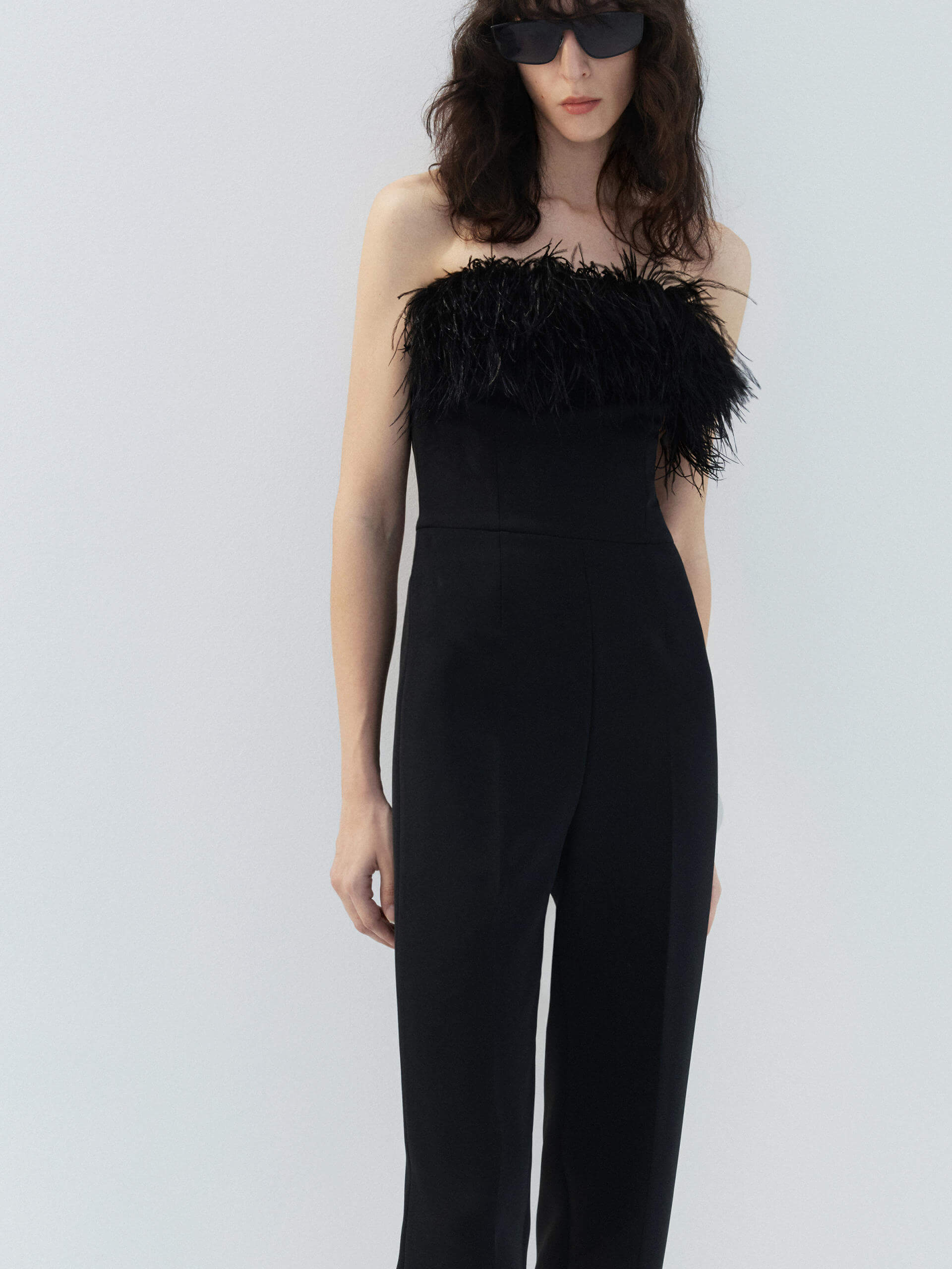 MO&Co. Noir Women's Feather Detail Fitted Jumpsuit Black features feather embellishments and a sleek straight-leg, strapless silhouette with a flattering fitted waist, ideal for a night out.