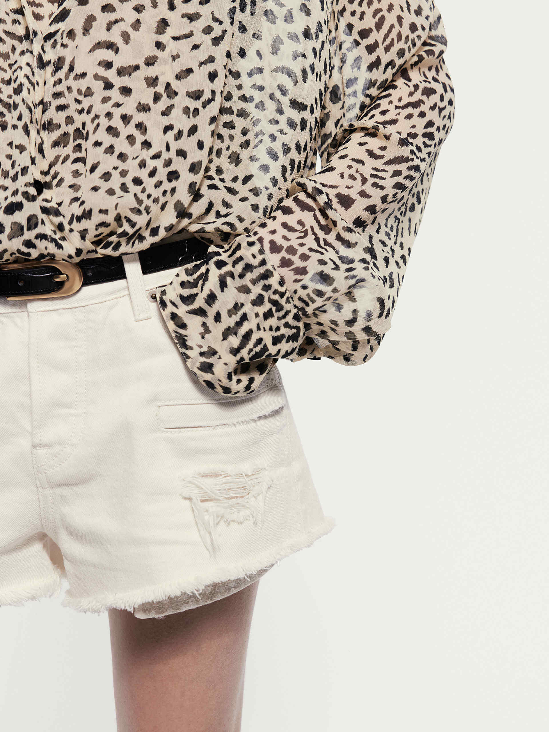 MO&Co. Noir Women's Fringed Denim Shorts in White. Crafted from high-quality Turkish cotton, these shorts feature a trendy distressed design and sequin-decorated longer pockets for a touch of glamour.