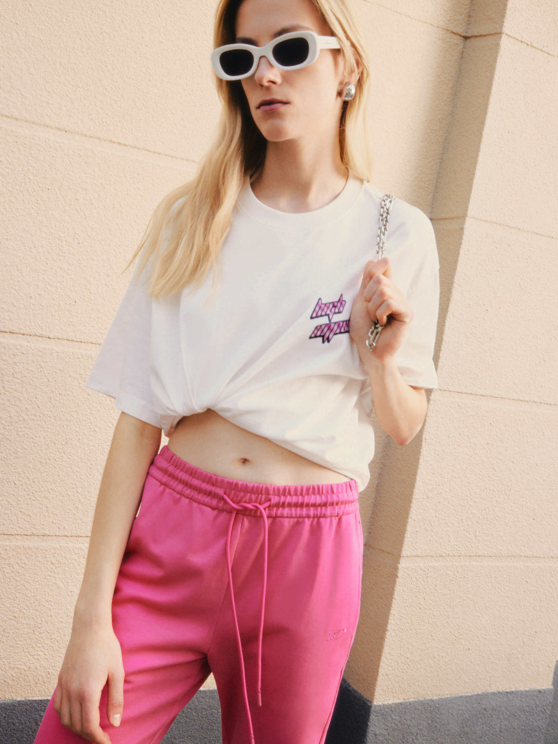 MO&Co.'s Drawstring Waist Causal Flared Sweatpants in Hot Pink. Crafted from soft cotton, these trousers feature a relaxed fit with drawstrings and elastic waistband for comfort. They also come with flared legs and double side pockets with MC embroidery details.