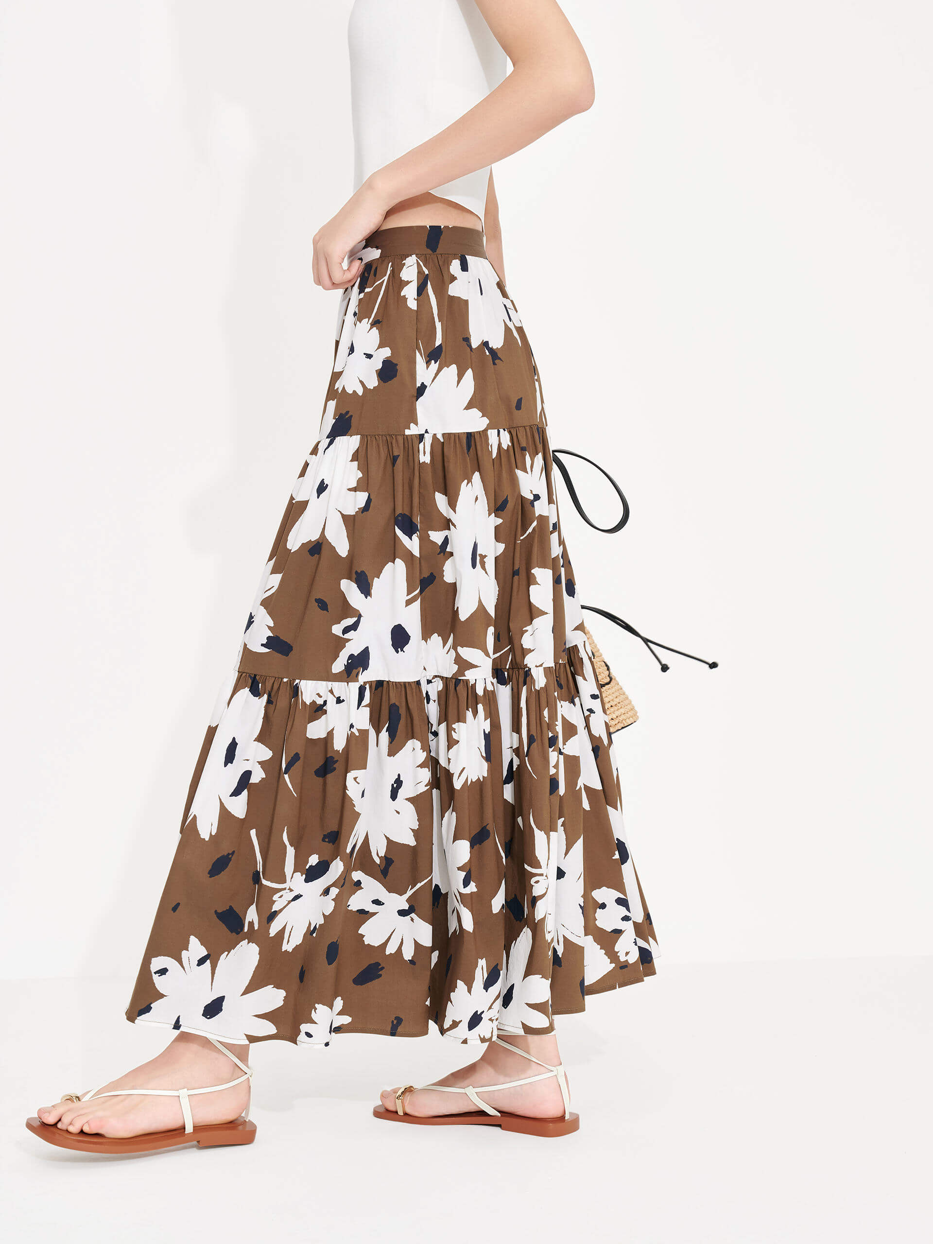 MO&Co. Women's Tiered Floral Print Maxi Skirt in Brown features a flowy fit, high waist and pleated design. Plus, the bold floral print and side zipper closure create a standout style.