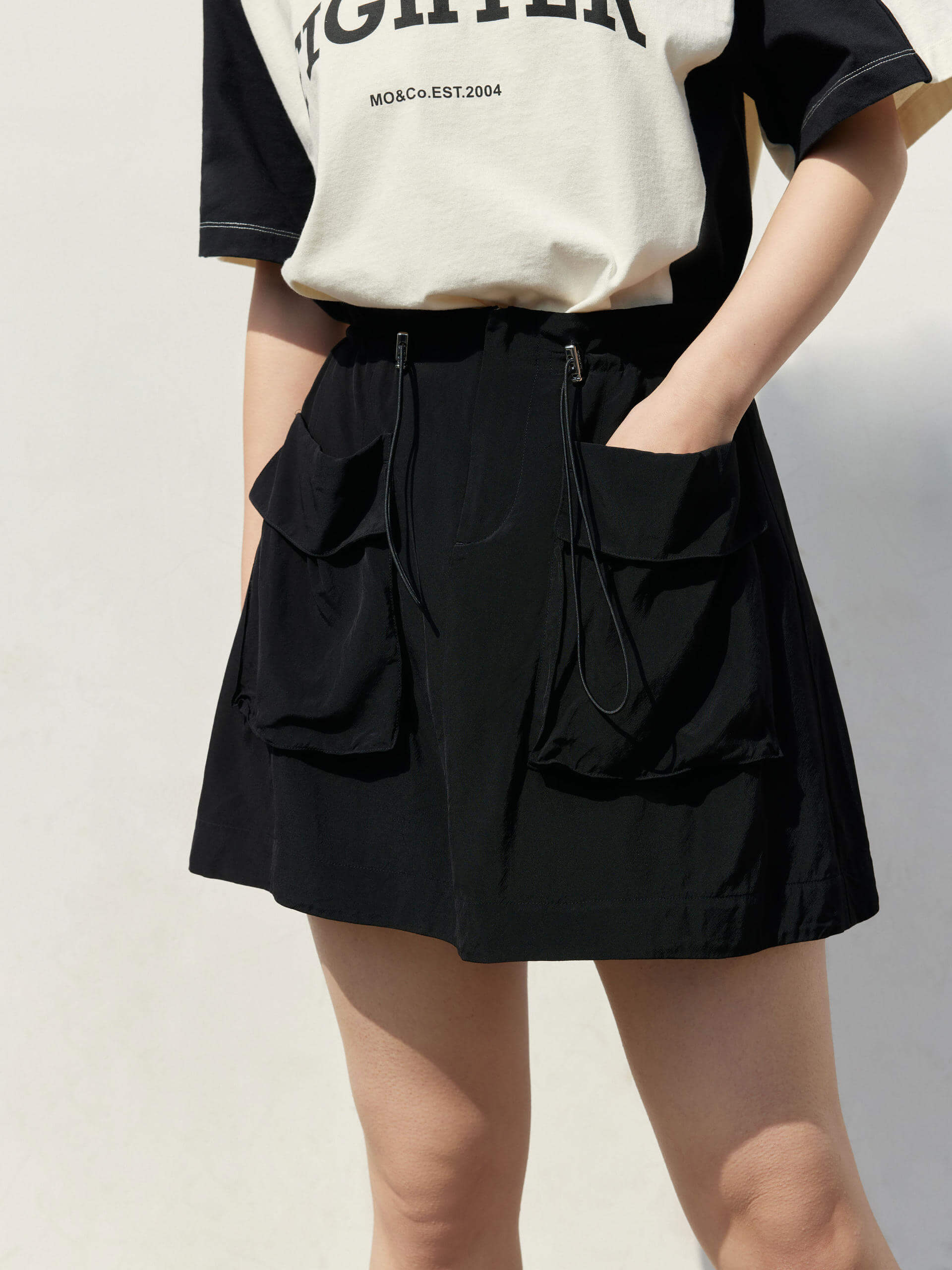 Black Drawstring Cargo Mini Skirt is ideal for everyday wear. It features a mini length, adjustable drawstring waist and front cargo pockets, perfect for your convenience.