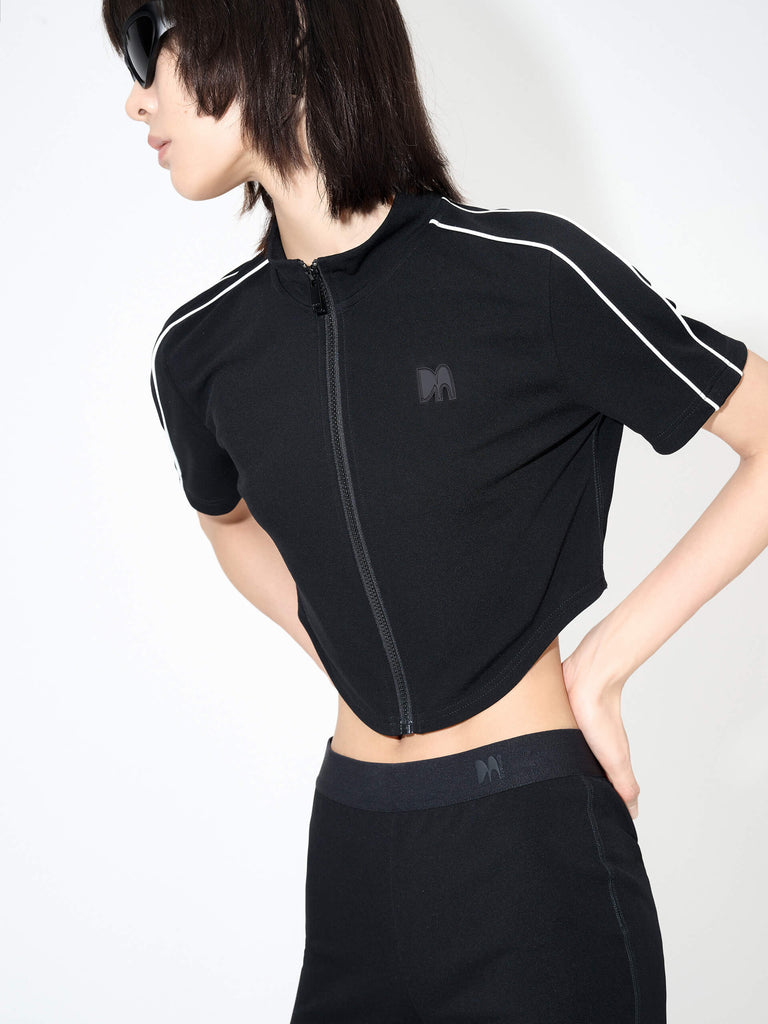 MO&Co. Women's Triacetate Blend Cropped Jacket in Black features a short athleisure silhouette with a curved hem, zipper closure, and tight fit. Short sleeves with contrasting details are paired with back pleating details that make the jacket stiff, resisting shape changes