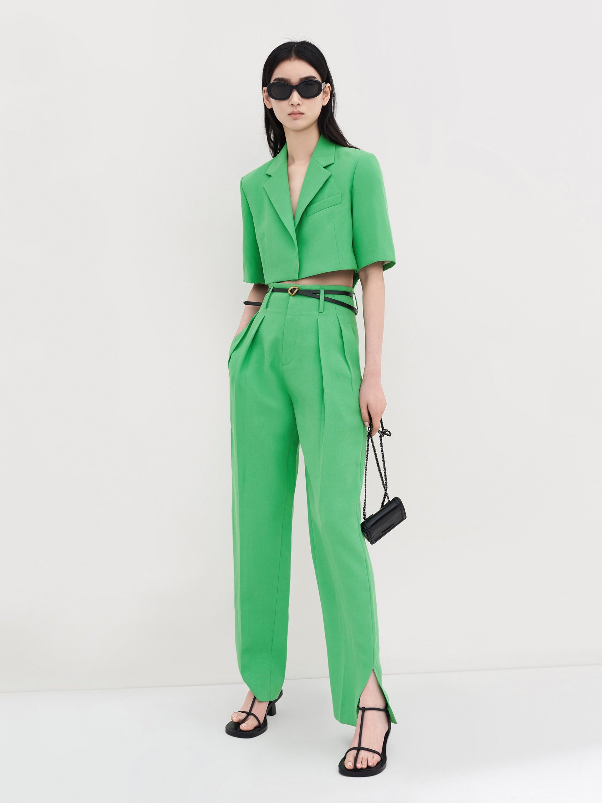 MO&Co. Women's Pleated Suit Pants with Belt in Green features high-rise, slit detail at hems, straight leg fit.