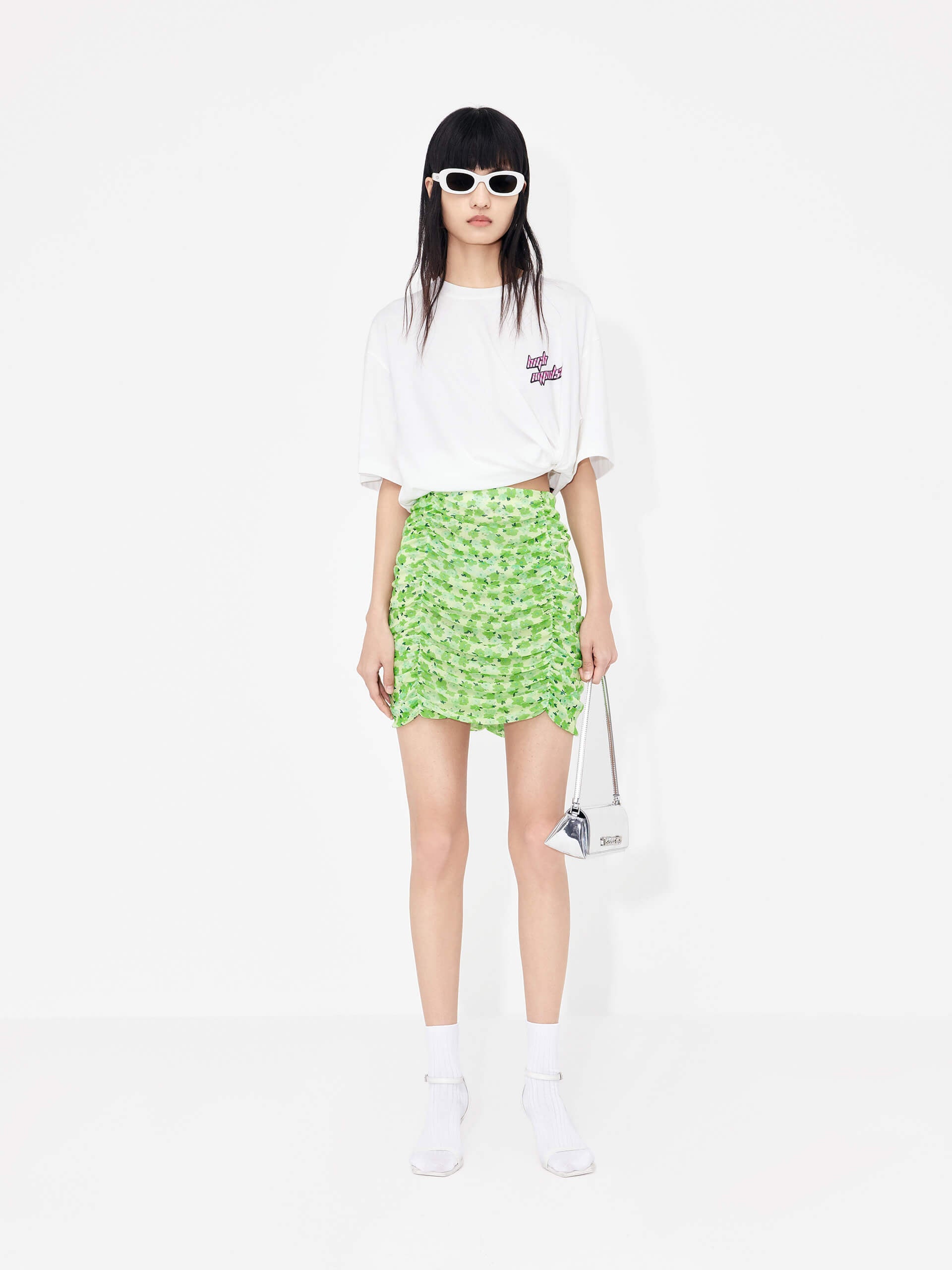 The MO&Co Women's Pleated Floral Print Mini Skirt in Green is a stylish wardrobe staple perfect for a polished look. Crafted from lightweight mesh with a pleated design, it features a classic flower print and draped detailing. A hidden side zipper and inner lining provide a comfortable, secure fit.