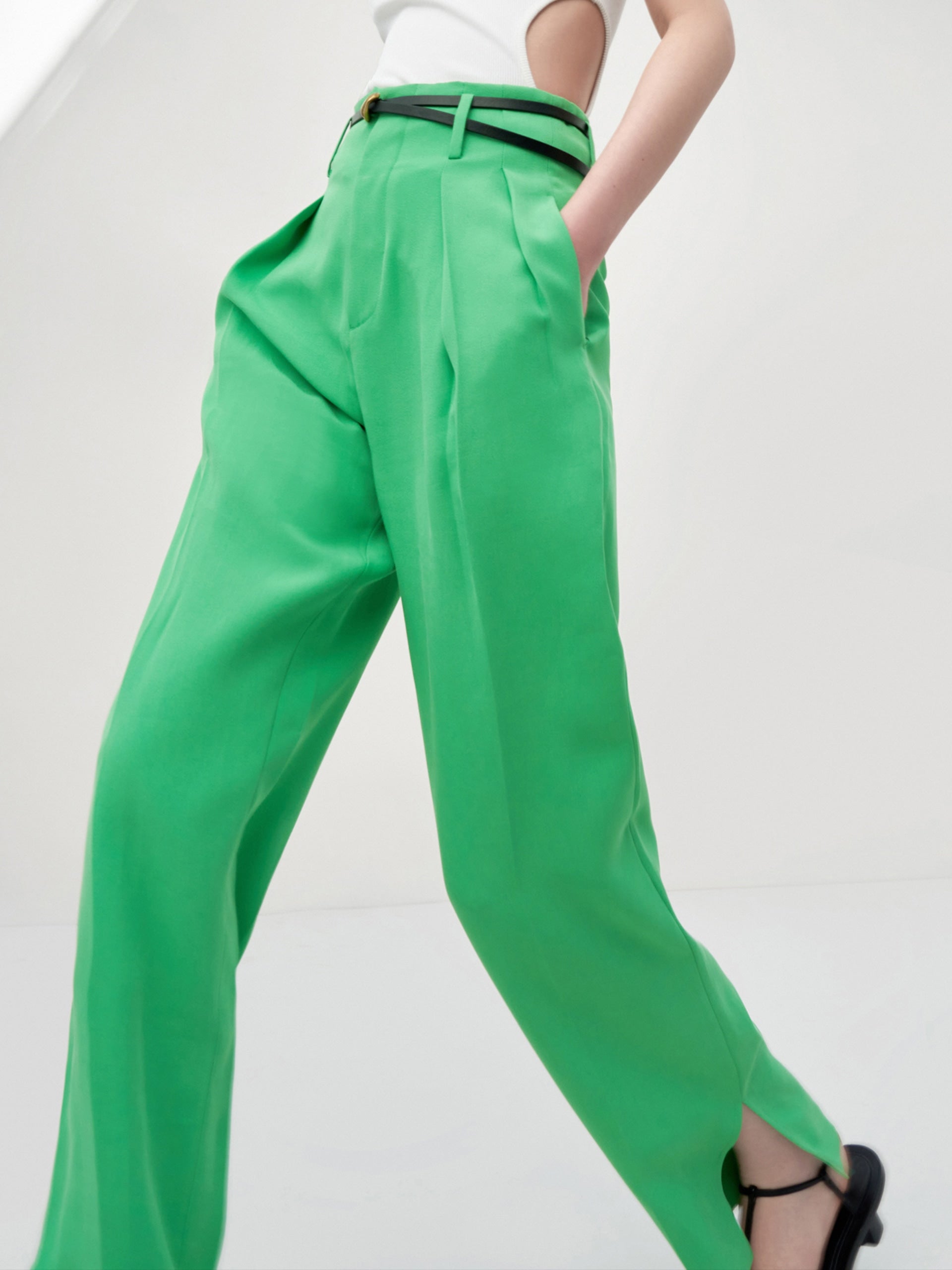 MO&Co. Women's Pleated Suit Pants with Belt in Green features high-rise, slit detail at hems, straight leg fit.